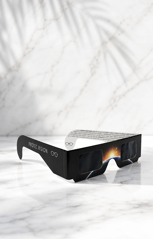 Gafas de eclipse homologadas Protec Vision con filtro solar, sobre una superficie de mármol blanco