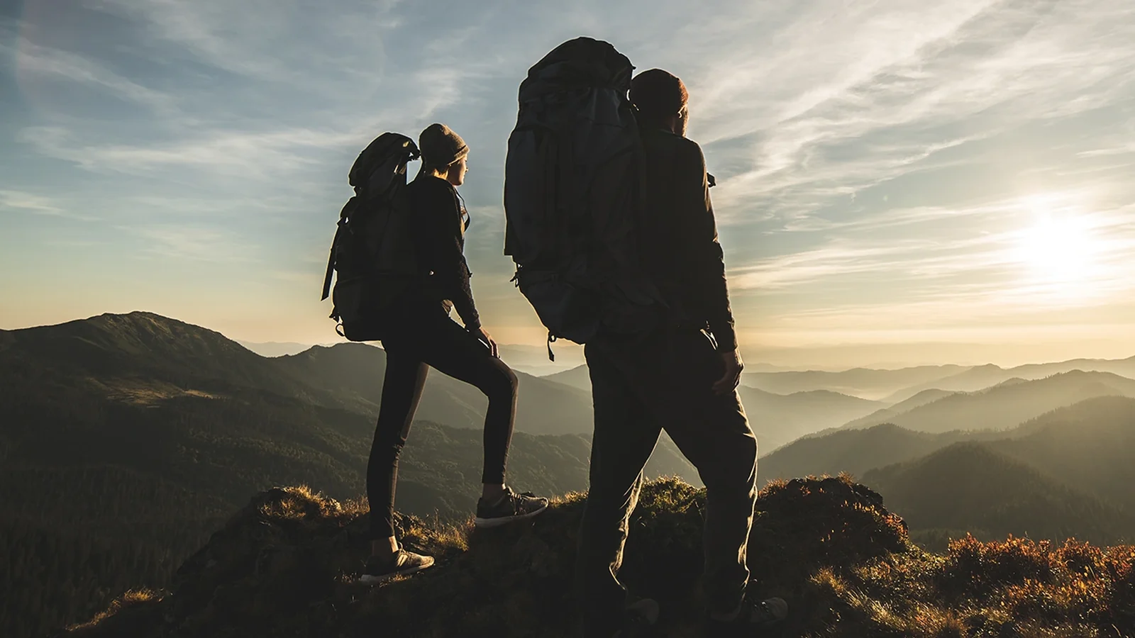 Dos excursionistes amb motxilla en una cresta de muntanya d'Andorra al capvespre, a punt per a una ruta de senderisme